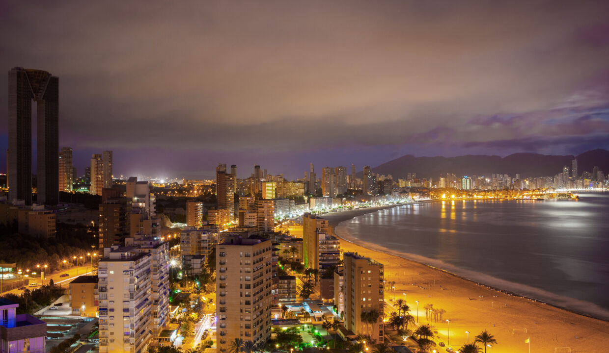 Panorama of the coastal city at sunset with lights reflected in sea